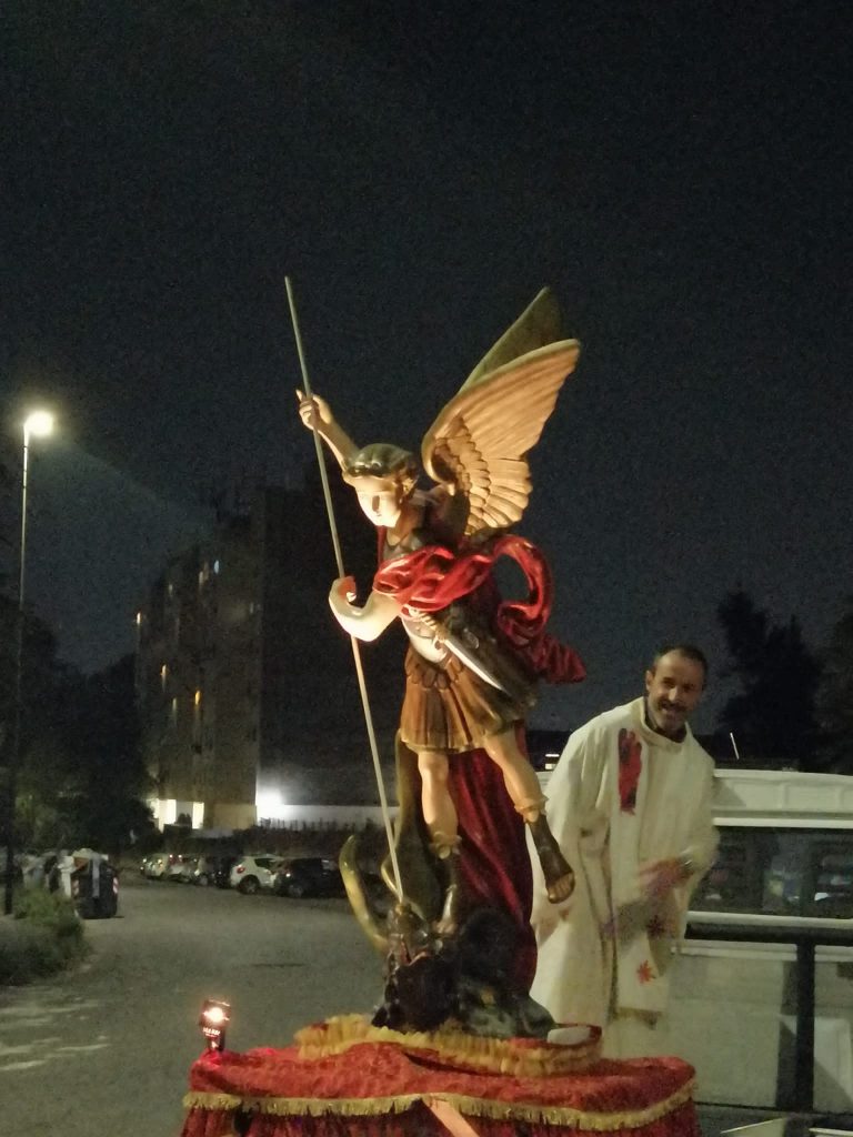 La statua di san Michele Arcangelo, accompagnata dal parroco don Gian Marco Merlo, è portata in giro nel quartiere di Pietralata a bordo di un carroattrezzi.